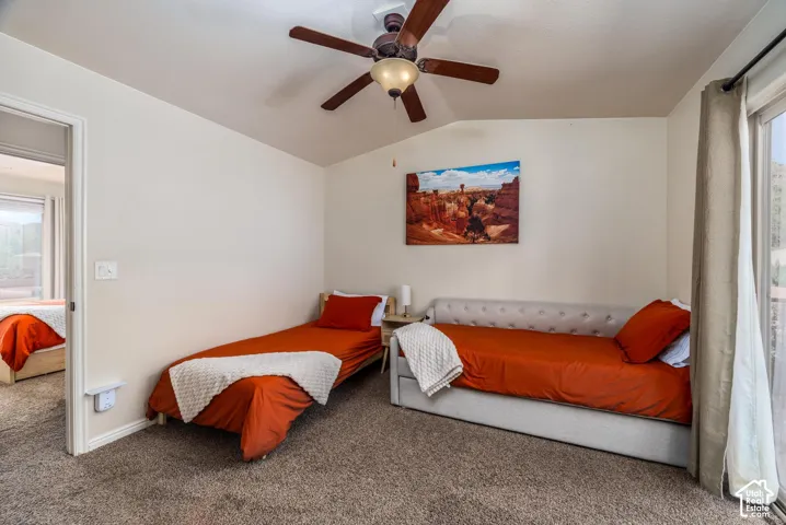 Carpeted room featuring a ceiling fan with integrated lighting, a sliding glass door, and a painted interior wall