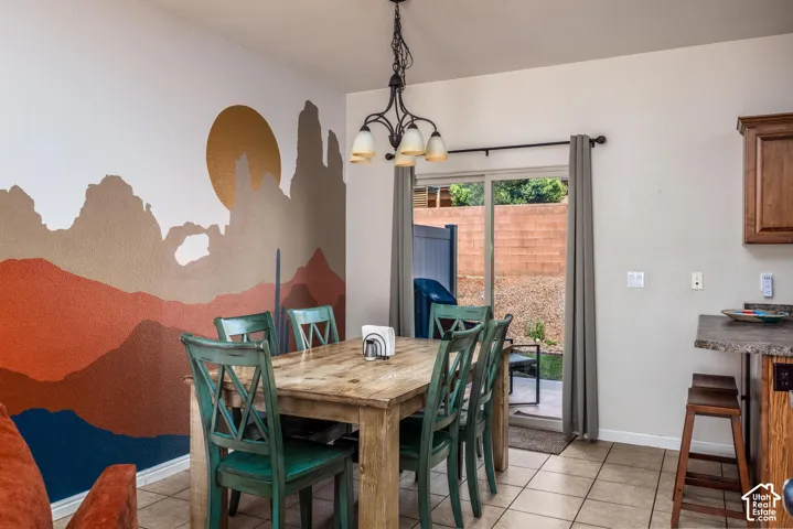 Dining area featuring a decorative wall mural, tile flooring, and a multi-light chandelier