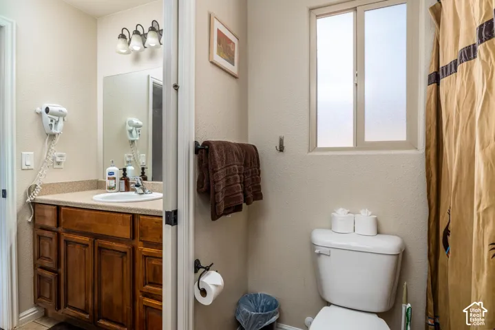 Bathroom featuring a wood-finish vanity with a built-in sink, a wall-mounted mirror, and a three-light fixture