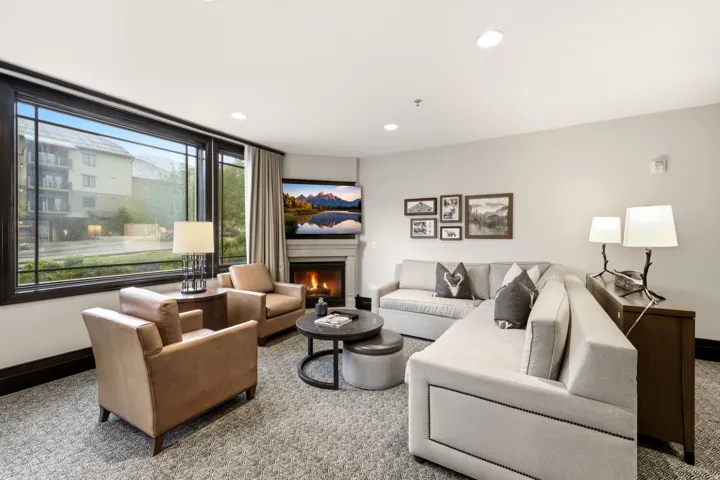 Living area featuring a corner fireplace with a mantel, large picture windows, recessed lighting, and soft carpet flooring
