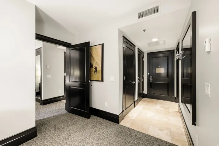 Hallway featuring dark paneled doors with contrasting light walls