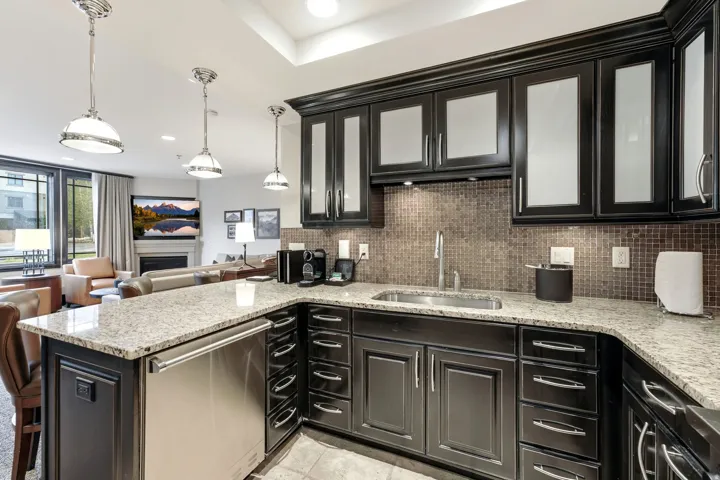 Kitchen featuring dark wood cabinetry with upper glass-front doors, granite countertops, and a mosaic tile backsplash