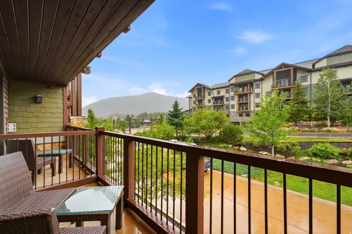 Private balcony featuring a wood-plank ceiling, wood railing with metal balusters, and stone accents