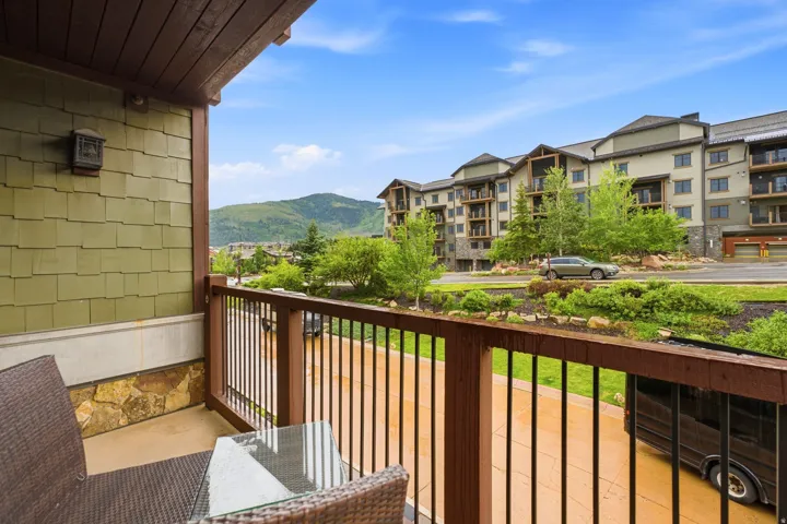 Private balcony featuring a wood railing, metal balusters, and a stone accent wall