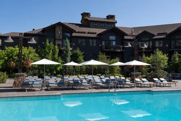 Expansive outdoor pool with a surrounding stone-finish deck and multiple chaise lounges