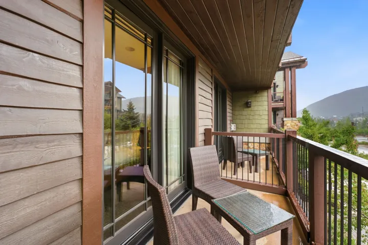 Private balcony featuring a wood-panel ceiling, durable railing, and mountain scenery
