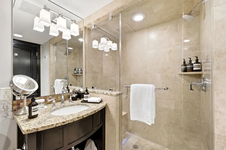 Bathroom featuring a curved vanity with a granite-finish countertop and an undermount sink