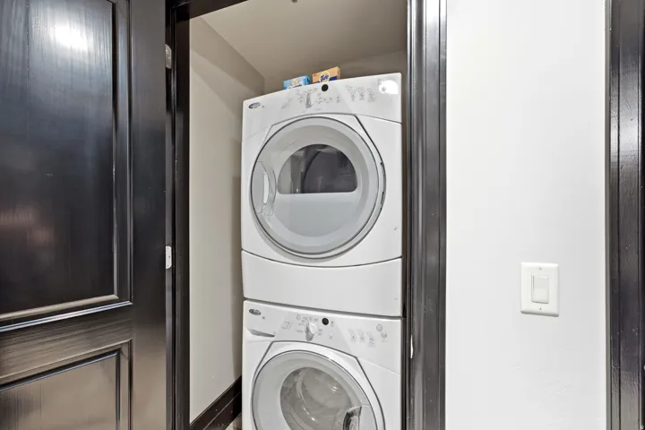 Dedicated laundry closet featuring a white stacked washer and dryer unit