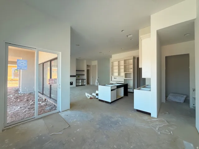 Open-concept living space featuring polished concrete flooring, abundant natural light from glass sliding doors, and seamless sightlines to the kitchen area