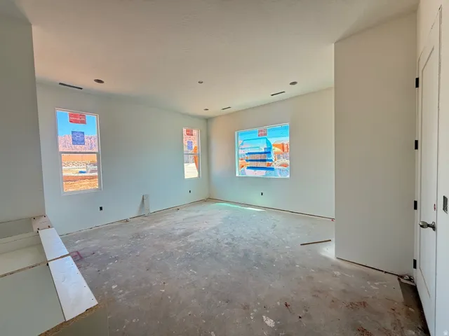 Recessed lighting, painted walls, multiple windows, and a doorway with hardware