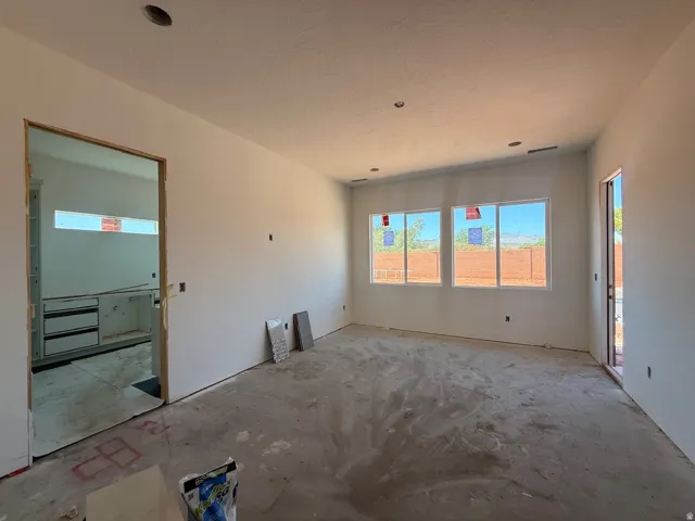 Open-concept space with multiple windows, recessed lighting, and a doorway to an additional room featuring built-in cabinetry