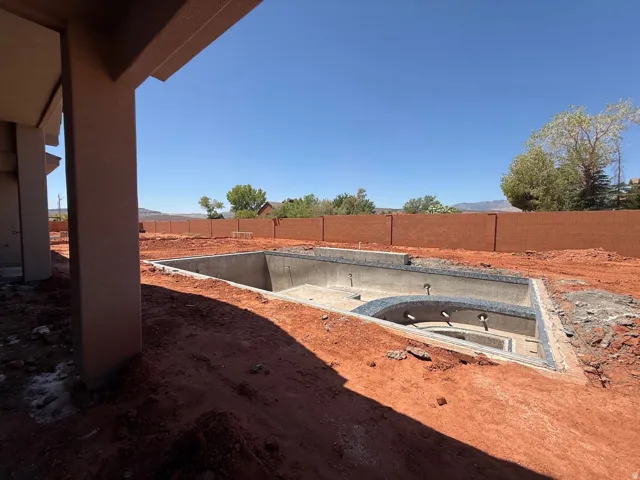 New construction with a built-in pool and spa, featuring an adjoining covered patio