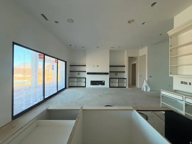 Expansive window wall with black framing, built-in fireplace, custom built-in shelving, recessed ceiling lighting, and custom cabinetry