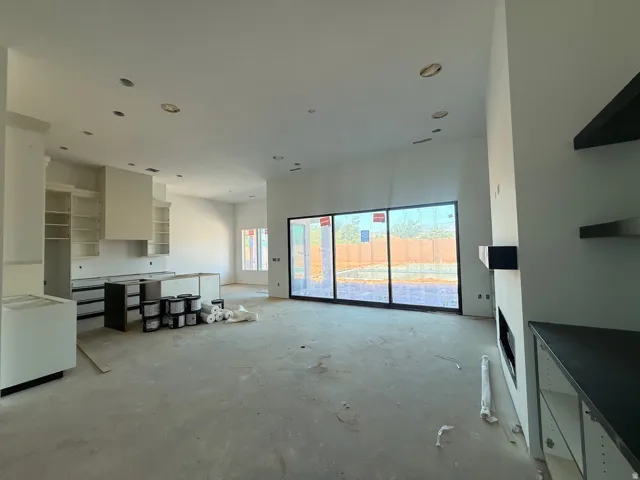 Expansive open-concept space featuring high ceilings, recessed lighting, a modern fireplace, built-in shelving, and large sliding glass doors