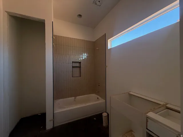 Built-in bathtub with vertical tile surround and integrated shower niche