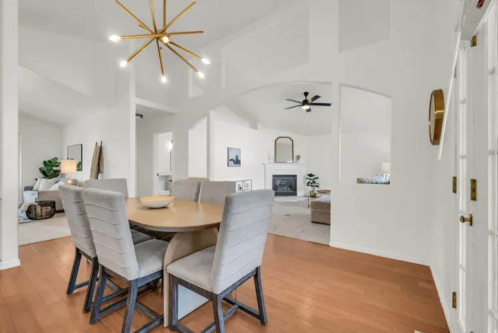 Open-concept dining area featuring wood-finish flooring, a contemporary sputnik chandelier, and arched doorways
