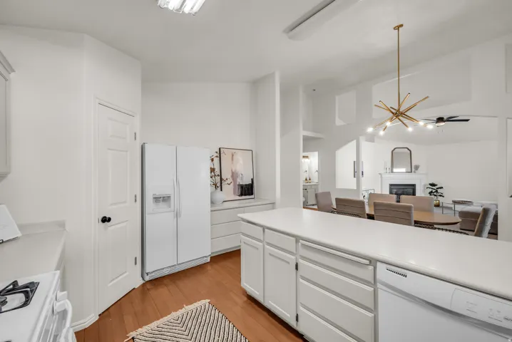 Kitchen island with white cabinetry, integrated dishwasher, and light-toned countertop