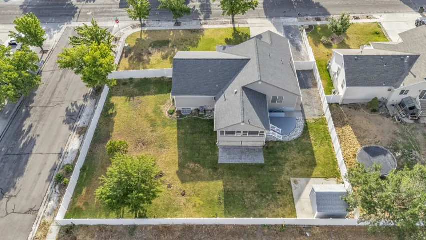 Expansive fenced backyard featuring a paved patio area, detached storage shed, and mature trees