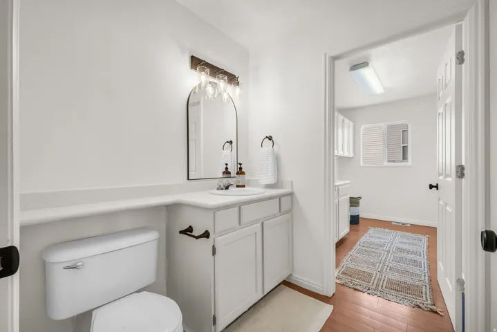 Bathroom vanity featuring white cabinetry, a single basin sink, and a countertop with integrated backsplash