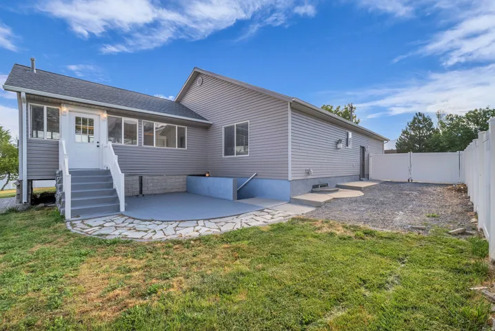 Rear exterior featuring grey siding, a white entry door, and a white staircase with railings