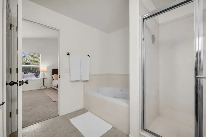 Bathroom featuring a glass-enclosed shower, built-in soaking tub, and tile flooring