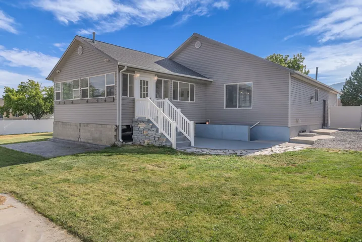 Gray siding exterior with white trim, featuring a sunroom addition and a lower-level patio