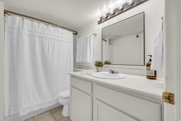 Bathroom featuring a white vanity with integrated sink, a large rectangular mirror, and a five-bulb vanity light fixture