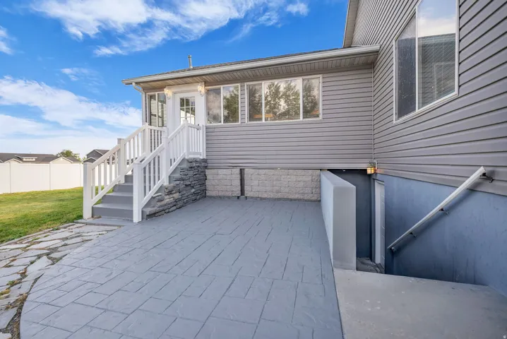 Exterior patio featuring stamped concrete, stone veneer accents, and a dedicated basement entrance