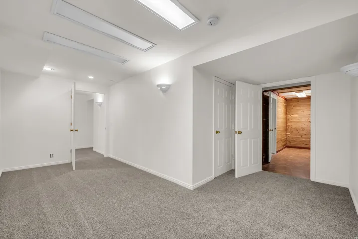 Carpeted room with recessed lighting and wall sconces