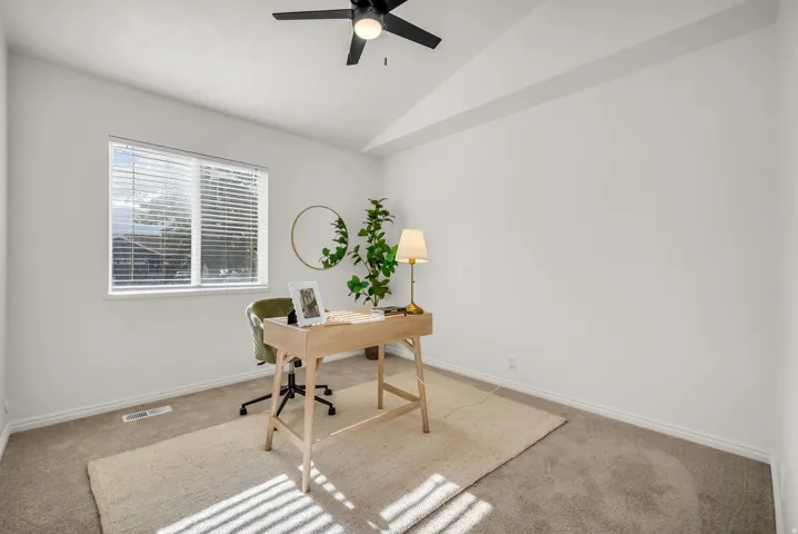 Vaulted ceiling room with an overhead fan, featuring a window with blinds, and neutral carpet flooring