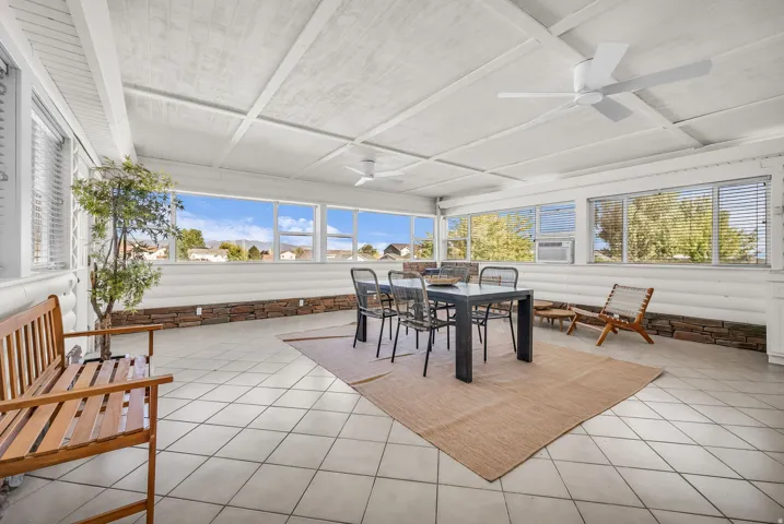 Sunroom featuring large windows, exposed beam ceiling, tile flooring, and stone base wall accents