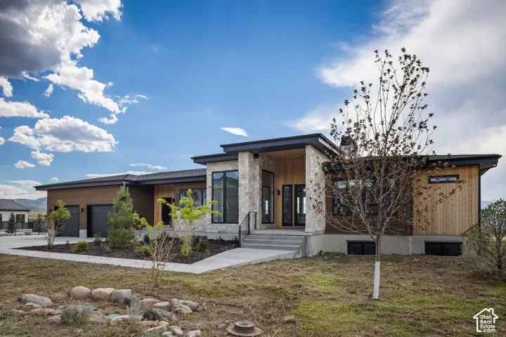 Modern architectural design featuring a prominent stone facade, wood siding, and large windows