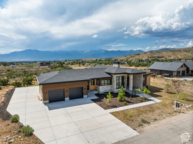Contemporary residence featuring a stone and wood-tone exterior, an attached two-car garage, and a concrete driveway