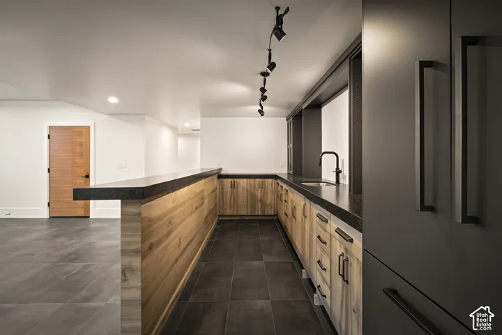 Kitchenette featuring wood-finish cabinetry, dark countertops, and a black faucet