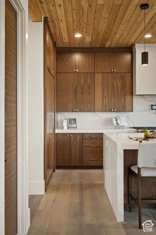 Kitchen featuring extensive wood cabinetry, light wood-finish flooring, and a wood plank ceiling