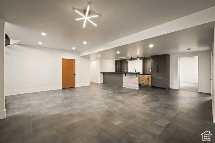 Open-concept recreation room featuring modern tile flooring, recessed lighting, and a contemporary linear chandelier