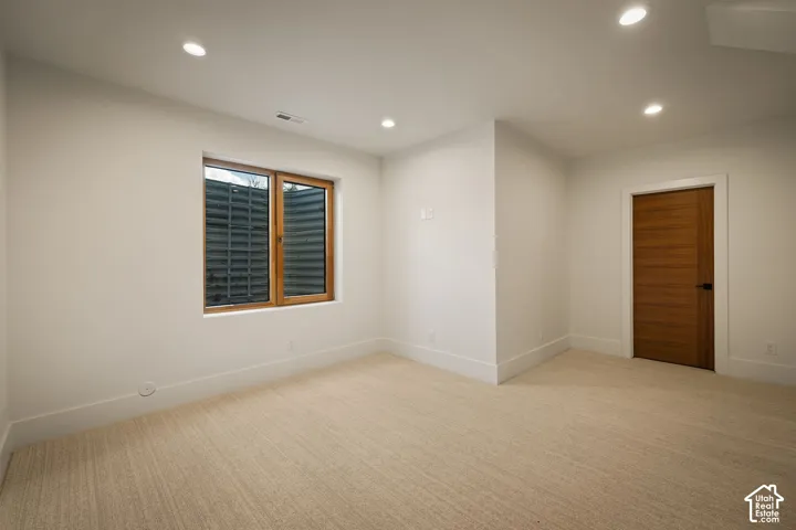 Carpeted room featuring recessed lighting, a window with a wood frame, and a solid wood door with a dark handle