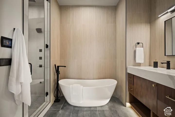 Contemporary bathroom featuring a freestanding soaking tub, a frameless glass-enclosed shower, a wood-finish vanity with a stone countertop, black fixtures, and light-toned wall paneling