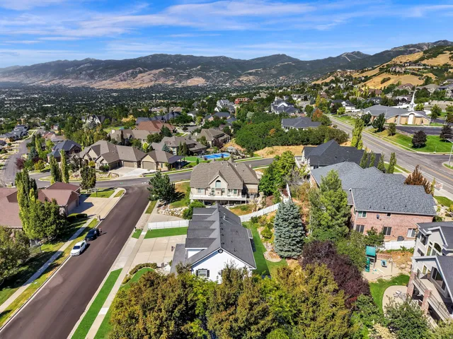Expansive residential area featuring a variety of architectural styles, mature landscaping, paved roadways, and mountainous backdrop