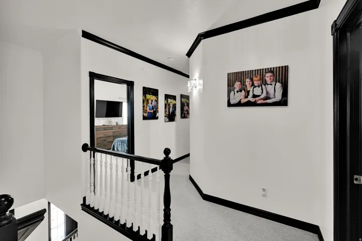 Upper-level hallway featuring a white spindle railing with a black handrail and newel posts