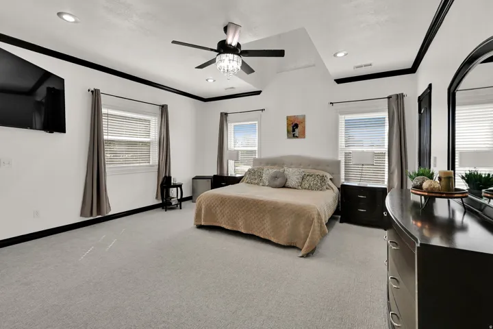 Spacious room featuring vaulted ceilings, recessed lighting, and a ceiling fan with a crystal light fixture
