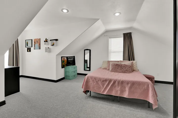 Bedroom featuring sloped ceilings, recessed lighting, light gray patterned carpet, a window with blinds, and dark baseboards
