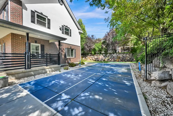Outdoor sports court with blue surface and white lines, surrounded by landscaping