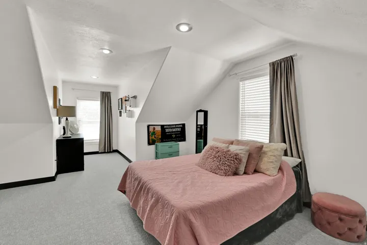 Carpeted room with sloped ceilings and recessed lighting