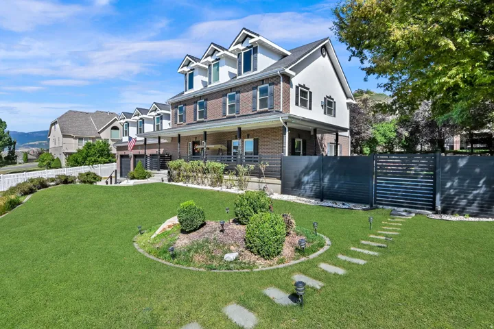Stately residential property featuring a brick and white siding exterior with dormer windows and black shutters
