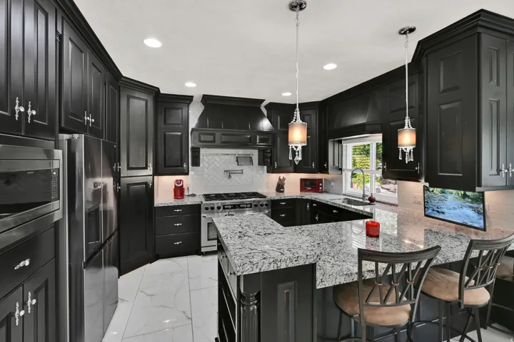 Kitchen featuring dark cabinetry, stainless steel appliances, a white herringbone tile backsplash, granite countertops, and white tile flooring