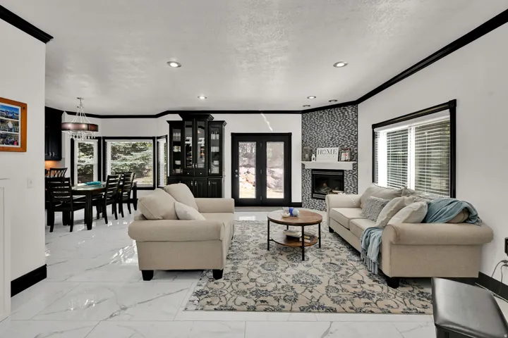Spacious living area featuring white marble-look flooring, a fireplace with a textured tile surround, and recessed lighting