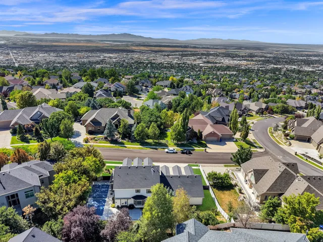 Expansive neighborhood aerial showcasing numerous residential properties with diverse architectural styles, mature landscaping, and curved street layouts