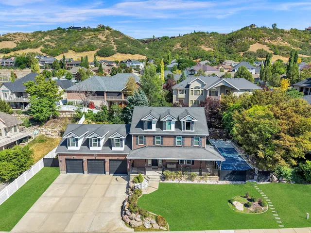 Brick facade residence featuring a three-car garage, covered front porch, and a dedicated sport court