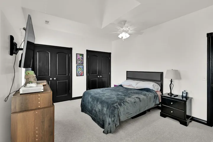 Bedroom featuring a vaulted ceiling with a ceiling fan, light gray carpeting, and white walls